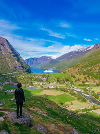 Rear view of man walking on mountain against sky