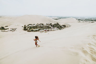 Full length of woman in swimwear running on a dune, huacachina,peru