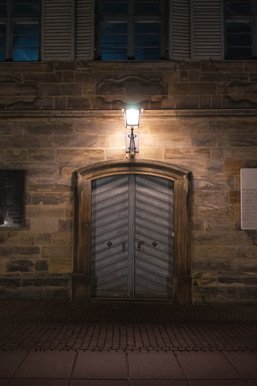 architecture, built structure, darkness, lighting equipment, building exterior, no people, illuminated, light, building, wood, lighting, street, wall, house, night, entrance, door, brick, city, outdoors, closed, window, wall - building feature