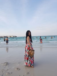 Portrait of woman standing at beach against sky