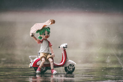 Full length of boy toy on wet car during rainy season