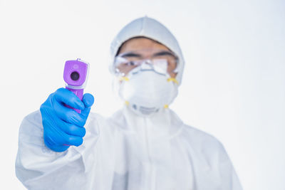 Portrait of boy wearing protective suit holding infrared thermometer