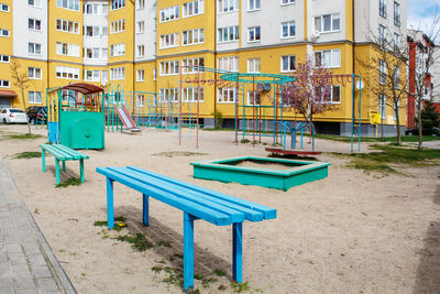 Empty benches in playground against buildings in city