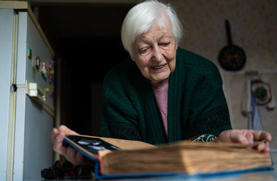 Portrait of old woman looking album at home