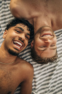 Directly above view of shirtless male friends lying down together