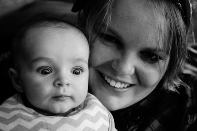 Close-up of smiling mother with surprised baby