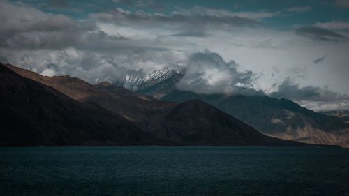 Scenic view of sea by mountains against sky