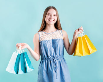 Portrait of smiling woman standing against blue background