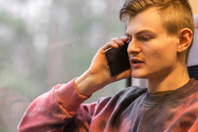 Young busy man calling on smartphone when he traveling by train, alking about business matters.