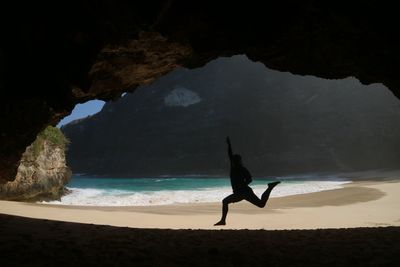 Rear view of man on rock at beach against sky