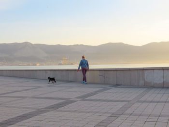 Woman with dog on mountain against sky