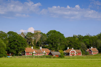 Houses and trees on field against sky