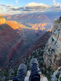 Low section of person on rock in mountains against sky