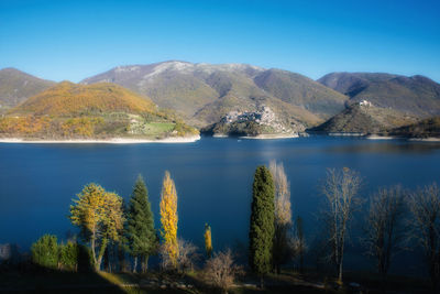 Scenic view of lake and mountains against clear blue sky