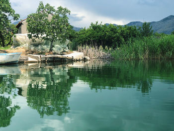 Reflection of trees and structures in lake against sky