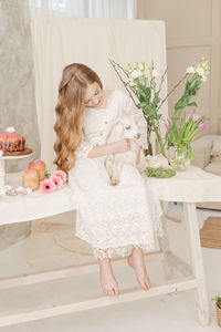 The girl is sitting at the easter table with cakes, spring flowers. happy easter celebration