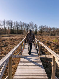 Full length of woman walking on boardwalk against clear sky