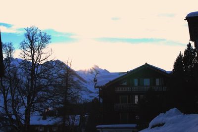 Houses and trees against sky during winter