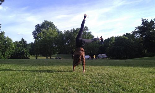 Woman doing handstand on grassy field