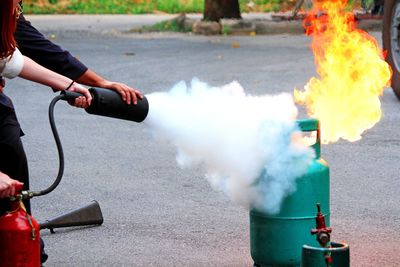 Cropped hands extinguishing fire on road