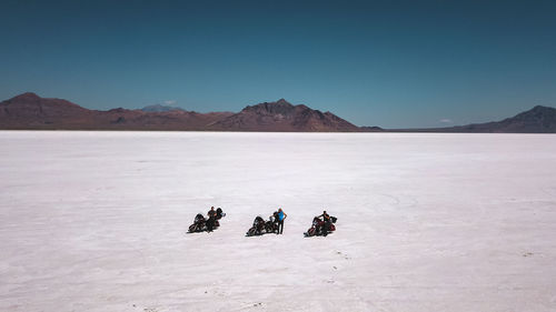 People in desert against clear sky