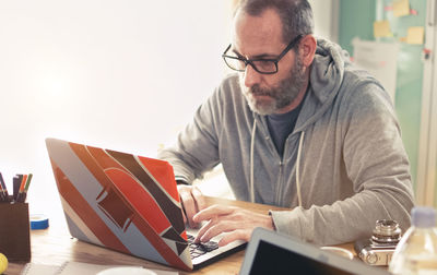 Man looking away by laptop on table by window