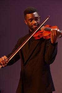 Midsection of man playing violin against black background