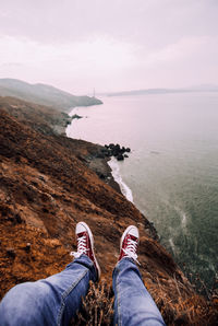 Low section of man on mountain by sea