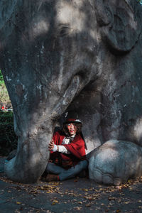 Man cosplaying mad hatter sitting under elephant statue