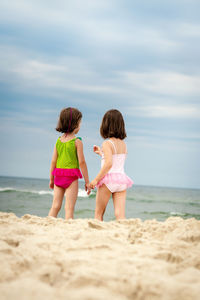 Rear view of women on beach against sky