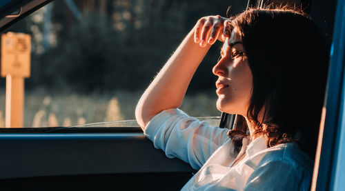 Side view of woman looking through window