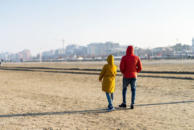 Rear view of couple walking at beach