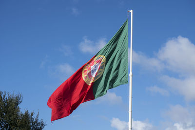 Low angle view of portuguese flag against blue sky