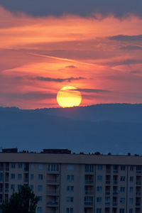 Scenic view of silhouette buildings against romantic sky at sunset