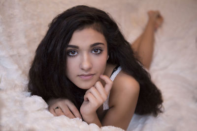 Portrait of young woman lying on bed