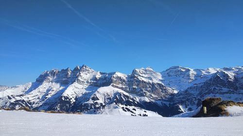 Scenic view of snowcapped mountains against clear blue sky