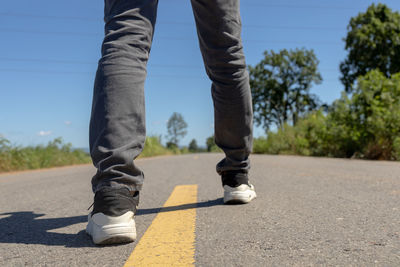 Low section of man standing on road