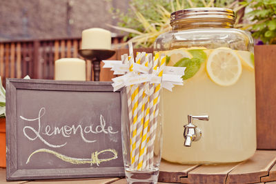 Close-up of fresh lemonade with straws in glass by chalkboard on table