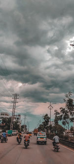 Cars on road against cloudy sky