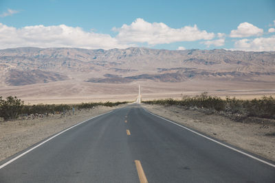 Road by desert against sky