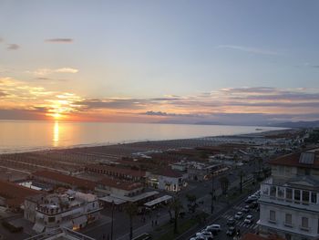 High angle view of buildings by sea against sky during sunset