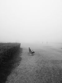 Empty bench on landscape against clear sky