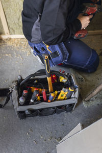 Midsection of female technician with drill machine by tool box