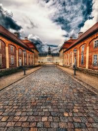 Cobblestone street amidst buildings against sky