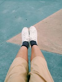 Low section of woman sitting above sidewalk 