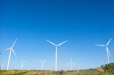 Wind turbines on land against clear blue sky