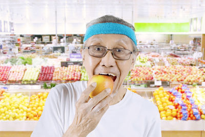 Portrait of senior man eating apple at market