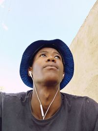 Close-up of young man listening music against clear sky