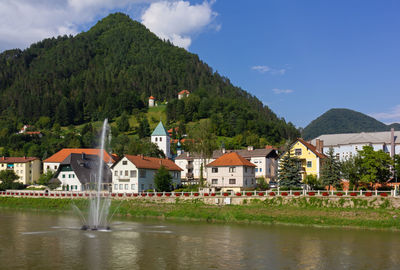 Houses by river and buildings against sky