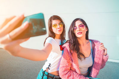 Young woman taking selfie from mobile phone with friend